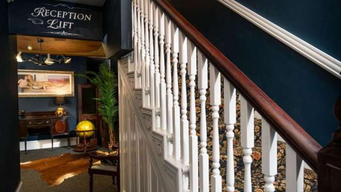 Eine Treppe in einem Haus mit einem Schild über der Treppe, das sagt " reception lift "