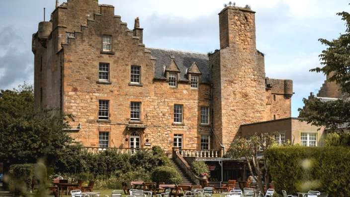 Eine Gruppe von Stühlen und Tischen vor einem großen Steingebäude