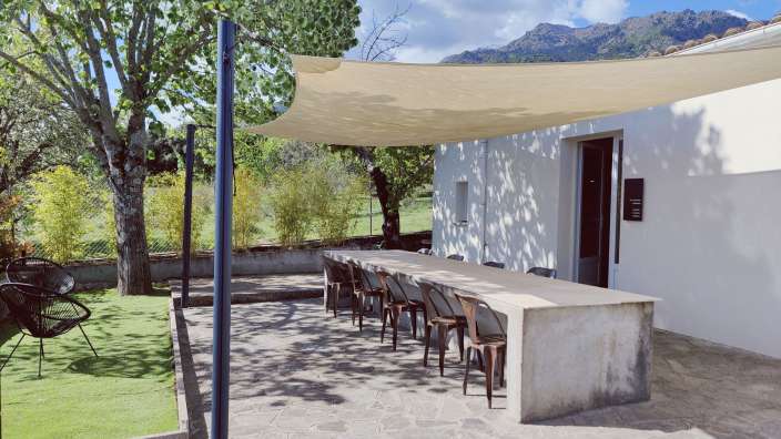 Ein Tisch und Stühle auf einer Terrasse unter einem Sonnenschirm
