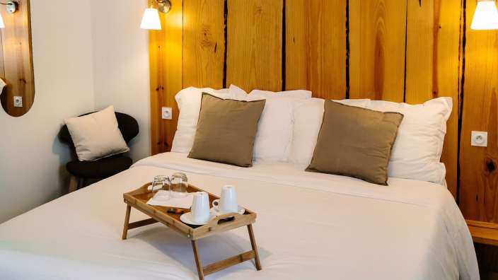 Ein Bett mit einem Holztablett mit Tassen und Gläsern darauf