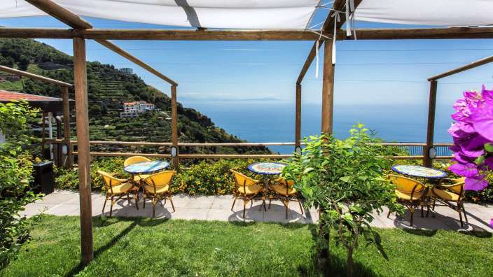 Tische und Stühle auf einer Terrasse mit Blick auf den Ozean