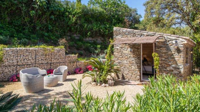 Ein kleines Steingebäude mit einem Tisch und Stühlen davor