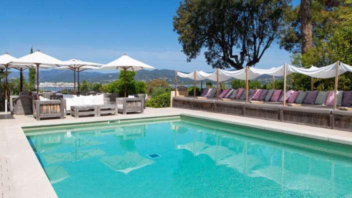 Ein großer Swimmingpool umgeben von weißen Sonnenschirmen und Stühlen