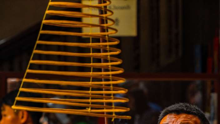 Ein Mann in einem grünen Hemd hält einen Incense-Stick in der Hand