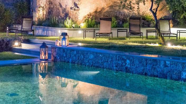 Ein Swimmingpool mit Liegestühlen und Laternen in der Nähe