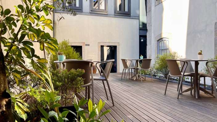 Tische und Stühle auf einem Holzdeck vor einem Gebäude