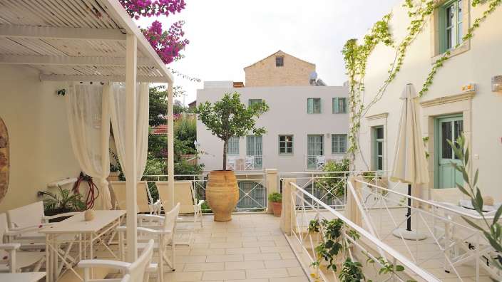 Ein Balkon mit einem Tisch und Stühlen und einer Vase mit einem Baum darauf