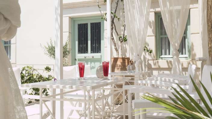 Ein Tisch und Stühle auf einer Terrasse mit weißen Vorhängen