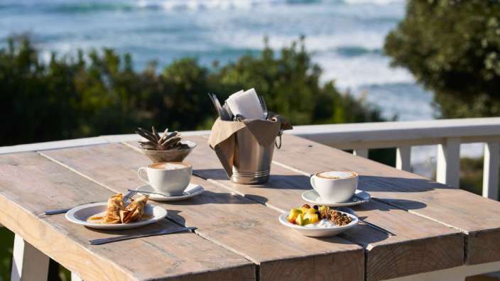 Ein Holztisch mit zwei Tassen Kaffee und zwei Tellern mit Essen darauf