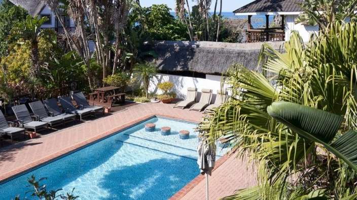 Ein großer Swimmingpool umgeben von Liegestühlen und Palmen