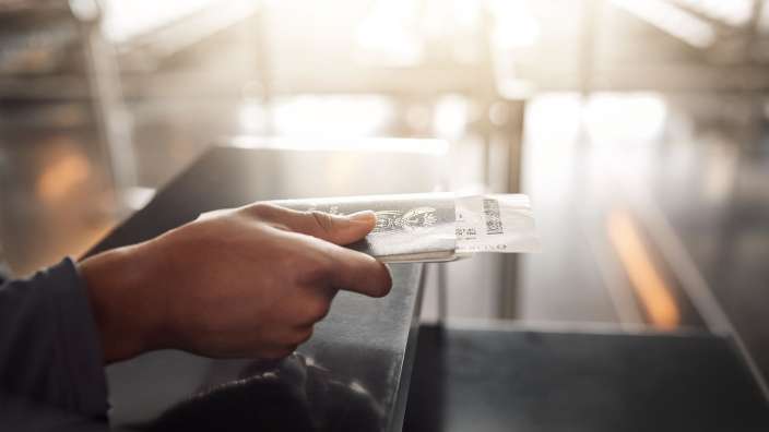 Eine Person hält einen Pass und einen Flugticket in der Hand