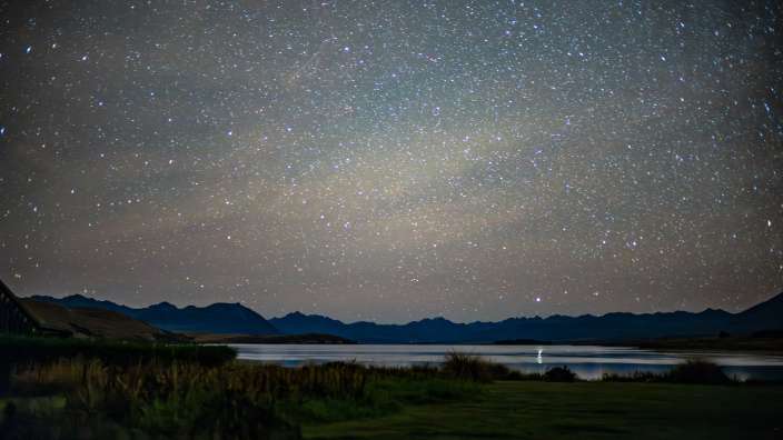Ein Sternhimmel über einem See mit Bergen im Hintergrund