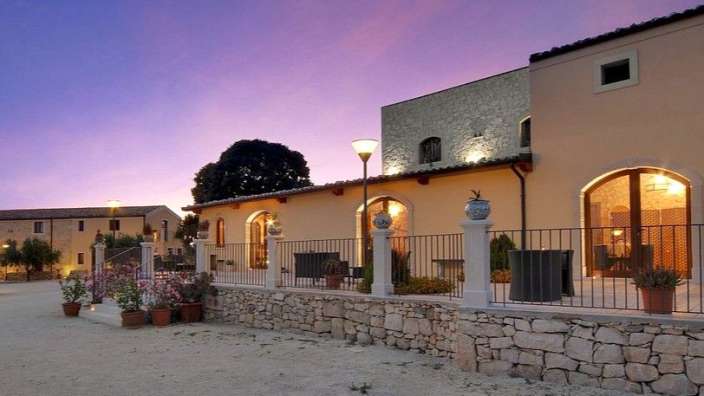 Ein großes Gebäude mit einem Zaun umgeben von Blumentöpfen