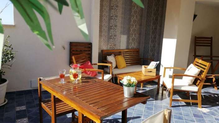 Eine Terrasse mit einem Tisch und Stühlen und einer Bank