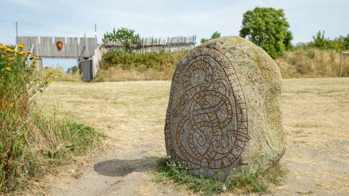 Ein großer Stein steht in einem Feld neben einem Holztor