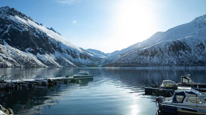 Eine Gruppe von Booten in einem See mit schneebedeckten Bergen im Hintergrund