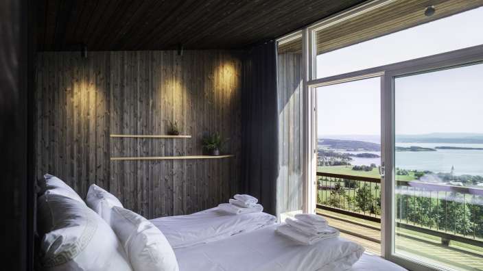 Ein Schlafzimmer mit zwei Betten und einem großen Fenster mit Blick auf einen See