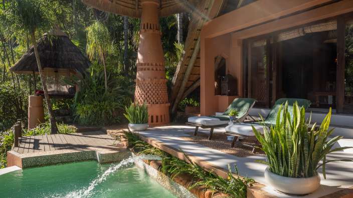 Ein Pool mit einem Wasserfall in der Nähe eines Hauses