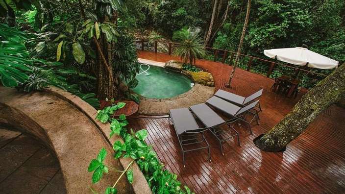 Ein Holzdeck mit einem Pool und Liegestühlen darauf