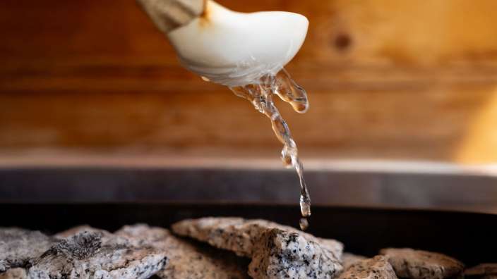 Wasser fließt aus einer weißen Schüssel in eine Sauna