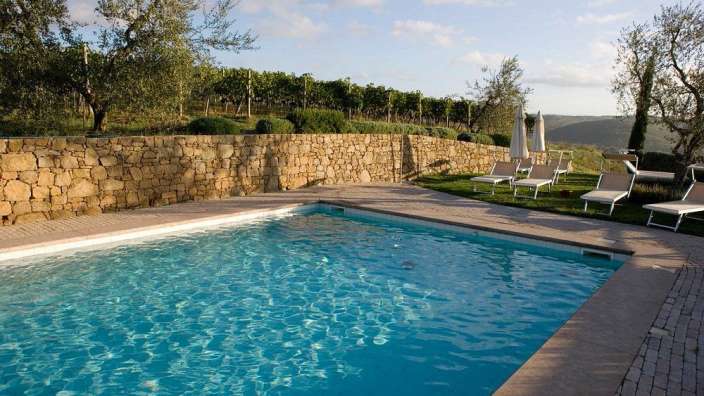 Ein großer Swimmingpool mit Liegestühlen und Sonnenschirmen umgeben