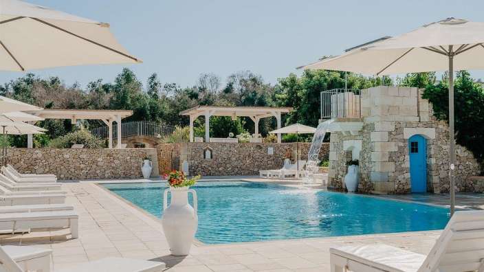 Ein großer Pool mit weißen Stühlen und Sonnenschirmen umgeben