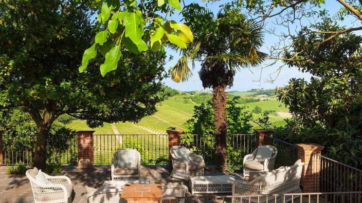 Eine Terrasse mit Stühlen und einem Tisch mit Blick auf einen Weinberg