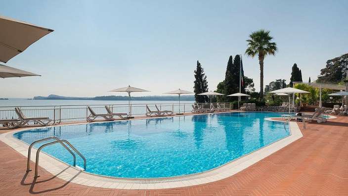 Ein großer Swimmingpool mit Liegestühlen und Sonnenschirmen umgeben