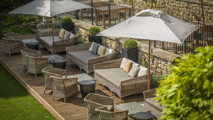 Eine Terrasse mit Couch und Stühlen und Regenschirmen