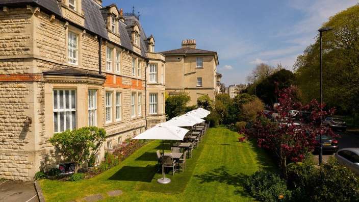 Eine Reihe von Tisch und Stühlen auf einem Rasen vor einem großen Gebäude