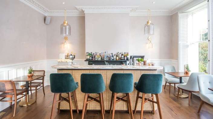 Eine Bar mit grünen Hockern und einem Tisch dahinter