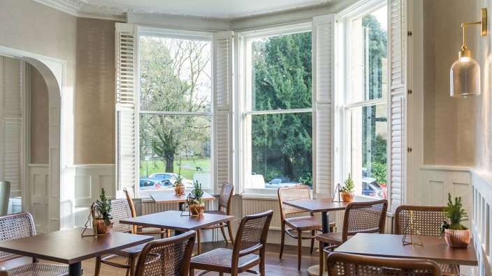 Tische und Stühle in einem Raum mit vielen Fenstern