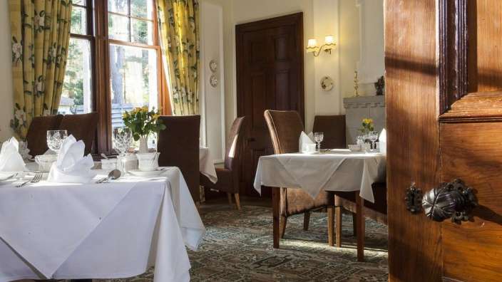 Ein Esszimmer mit Tischen und Stühlen mit weißen Tischdecken