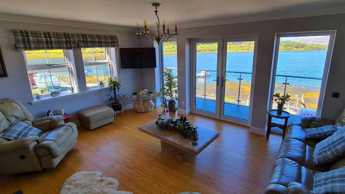 Ein Wohnzimmer mit vielen Fenstern und Blick auf den Ozean