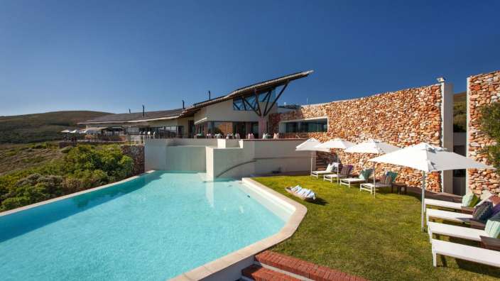 Ein großes Haus mit einem Pool und Liegestühlen davor