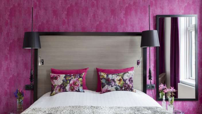 Ein Schlafzimmer mit rosa Wänden und einem Bett