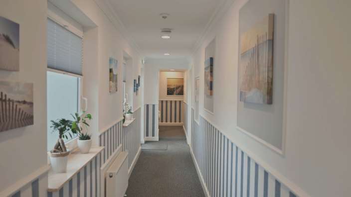 Ein Flur mit blau-weiß gestreiften Wänden und Bildern an den Wänden