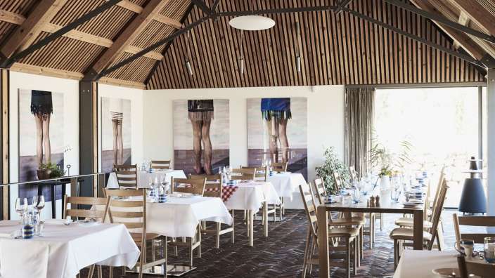 Ein Esszimmer mit Tischen und Stühlen und Gemälden an den Wänden