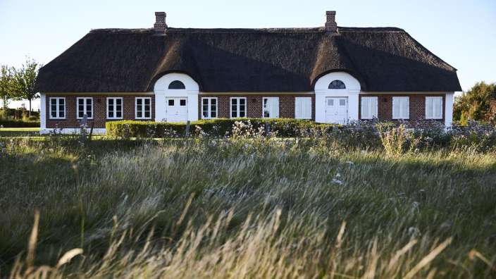 Ein großes Backsteinhaus mit Strohdach und weißen Fenstern