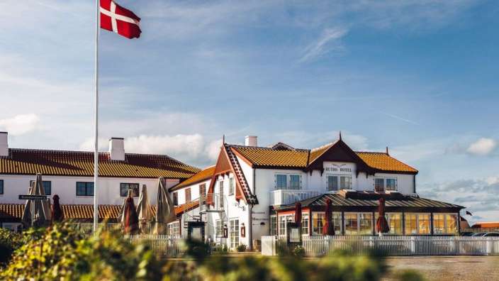 Eine dänische Flagge weht vor einem weißen Hotel