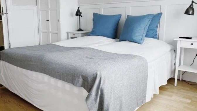 Ein Bett mit blauen Kissen und einer grauen Decke