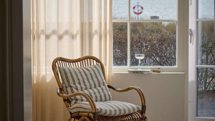 Ein Stuhl mit einem gestreiften Kissen sitzt vor einem Fenster