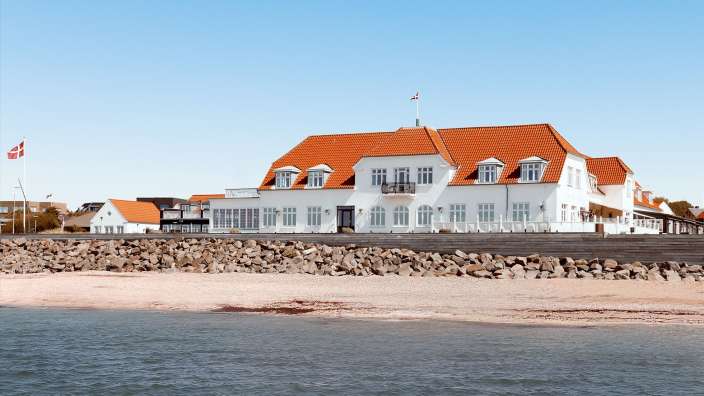 Ein großes weißes Gebäude mit einem roten Dach und einer Flagge darauf