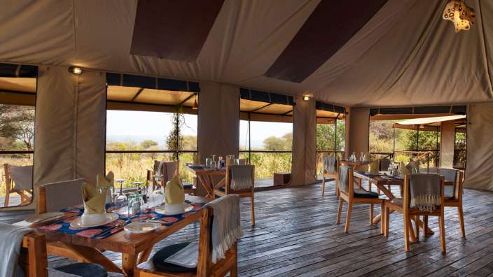 Tische und Stühle stehen in einem Zelt auf einem Holzboden