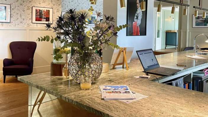 Ein Tisch mit einem Laptop und einer Vase mit Blumen darauf