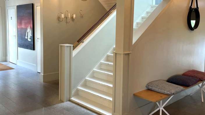 Ein Flur mit weißen Treppen und einer Bank mit Kissen darauf