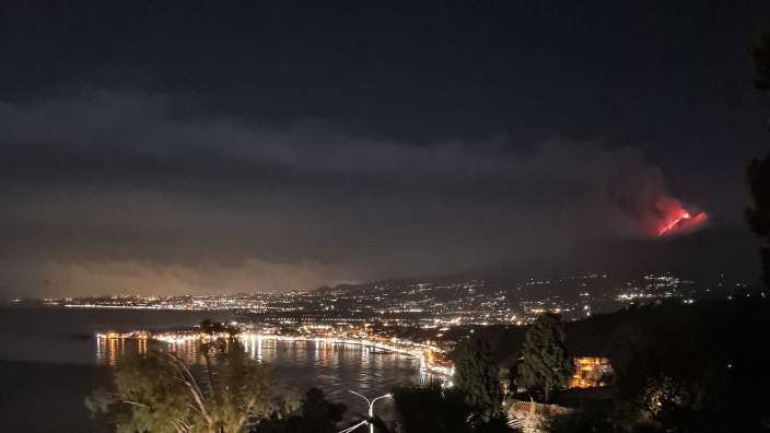 Eine Stadt bei Nacht mit einem Vulkan in der Ferne