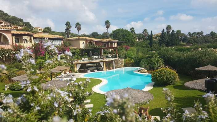 Ein großer Swimmingpool umgeben von Bäumen und Stühlen