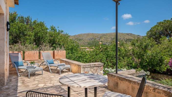 Ein Tisch und Stühle auf einer Terrasse mit Blick auf die Berge