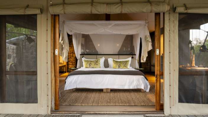 Ein Bett mit baldachin sitzt in einem Zelt